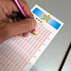 Ręka z ołówkiem zaznacza liczby na kuponie Lotto. Czy wartość głównej wygranej w lotto jest znana przed losowaniem?