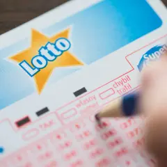 Dłoń z ołówkiem zaznacza liczby na kuponie Lotto. Czy to te same, dlaczego ludzie skreślają te same liczby co 80 innych zwycięzców?