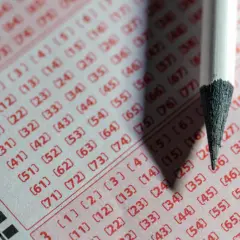 Zbliżenie na kupon lotto z zaznaczonymi liczbami i ołówkiem.