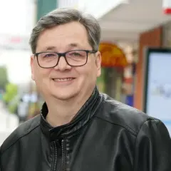 Uśmiechnięty mężczyzna w okularach i skórzanej kurtce. Czy to on wyjaśnia, dlaczego kultowy lektor programu przestał zapowiadać uczestników?