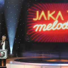 Prowadzący w studiu "Jaka to melodia?" z mikrofonem. Zastanawiasz się, ile kosztuje minuta reklamy w trakcie trwania tego programu?