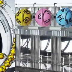 Losowanie liczb w lotto. Czy maszyny losujące lotto można zhakować lub zaprogramować wynik? Żółte kulki wirują w bębnie, a kolorowe w tubach.