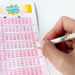 Dłoń zaznacza ołówkiem z logo Lotto wybrane mini lotto numery na kuponie.