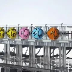 Sześć kolorowych kul z numerami w przezroczystej maszynie losującej.