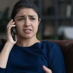 Zmartwiona kobieta rozmawia przez telefon, słysząc najgorsze opinie o loteriach "kredyt bez odsetek" dostępnych w internecie.