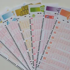 Kupony lotto z polami do zaznaczania liczb. Tabela systemu lotto jest widoczna na kilku kuponach.