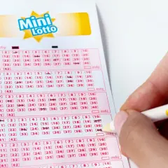 Dłoń z ołówkiem zaznacza liczby na kuponie Mini Lotto. Sprawdzanie lotto centrum wyniki to emocjonujący moment.