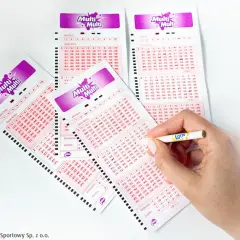 Tabela wygranych Multi Multi Plus z zaznaczonymi liczbami. Dłoń z ołówkiem zaznacza kolejne pola na kuponach.