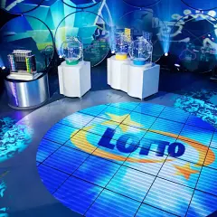 Scena studia lotto z kulami losującymi i ekranem z logo. Czy lottomilionerzy dostają ochronę osobistą od organizatora loterii?