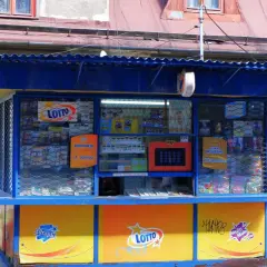 Kiosk Lotto z ekspozycją zdrapek i informacją o kumulacji. Dzieci siedzą obok, zastanawiając się, dlaczego kolektorzy nie chcą sprzedawać zdrapek z konkretnych numerów paczek.