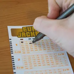 Ręka zaznacza liczby na kuponie Eurojackpot. Czy wygrana w Eurojackpot w Polsce jest opodatkowana inaczej niż w Lotto?