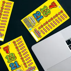 Zdrapki z numerami 7, 13, 21 leżą obok laptopa. Czy można wygrać w zdrapki grając wyłącznie w te same numery losów?