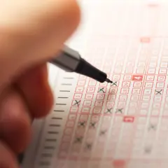 Ręka z długopisem zaznacza liczby na kuponie lotto, marząc o wygranej w jackpot.