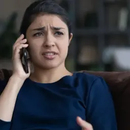 Zmartwiona kobieta rozmawia przez telefon, słysząc najgorsze opinie o loteriach "kredyt bez odsetek" dostępnych w internecie.