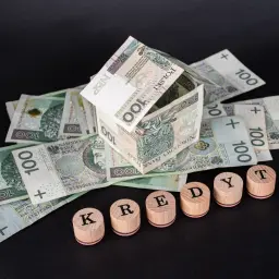 Dom z banknotów 100 zł i drewniane klocki z napisem "KREDYT". Uważaj na najczęstsze błędy w umowach pożyczkowych, które wykluczają z udziału w losowaniu.