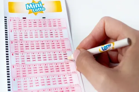 Ręka zaznacza liczby na kuponie Mini Lotto, licząc na wysokie wygrane w Multi Multi.