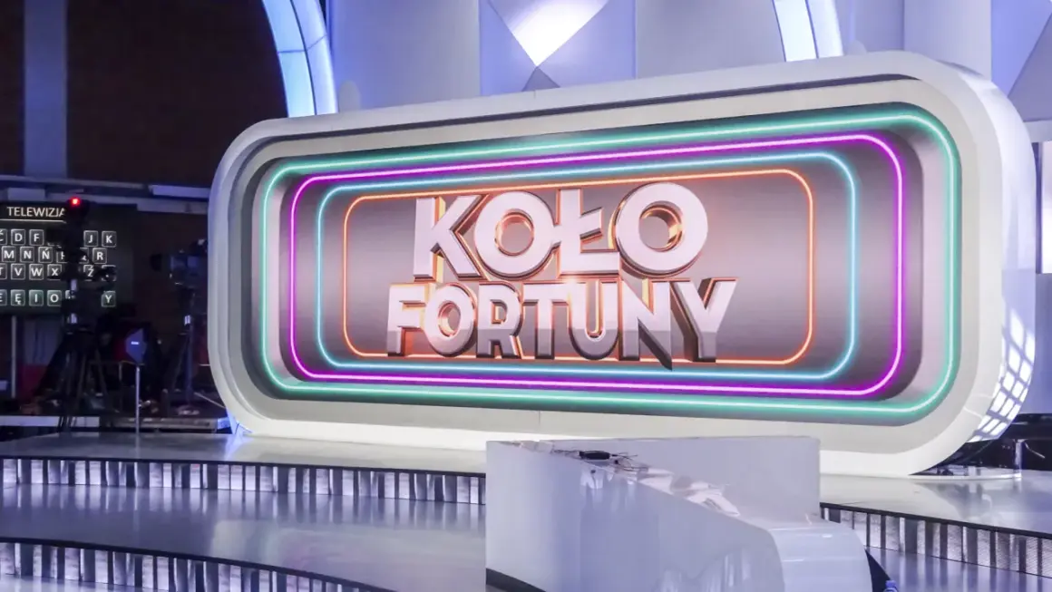 Logo "Koło Fortuny" na tle studia telewizyjnego z neonowym obramowaniem.