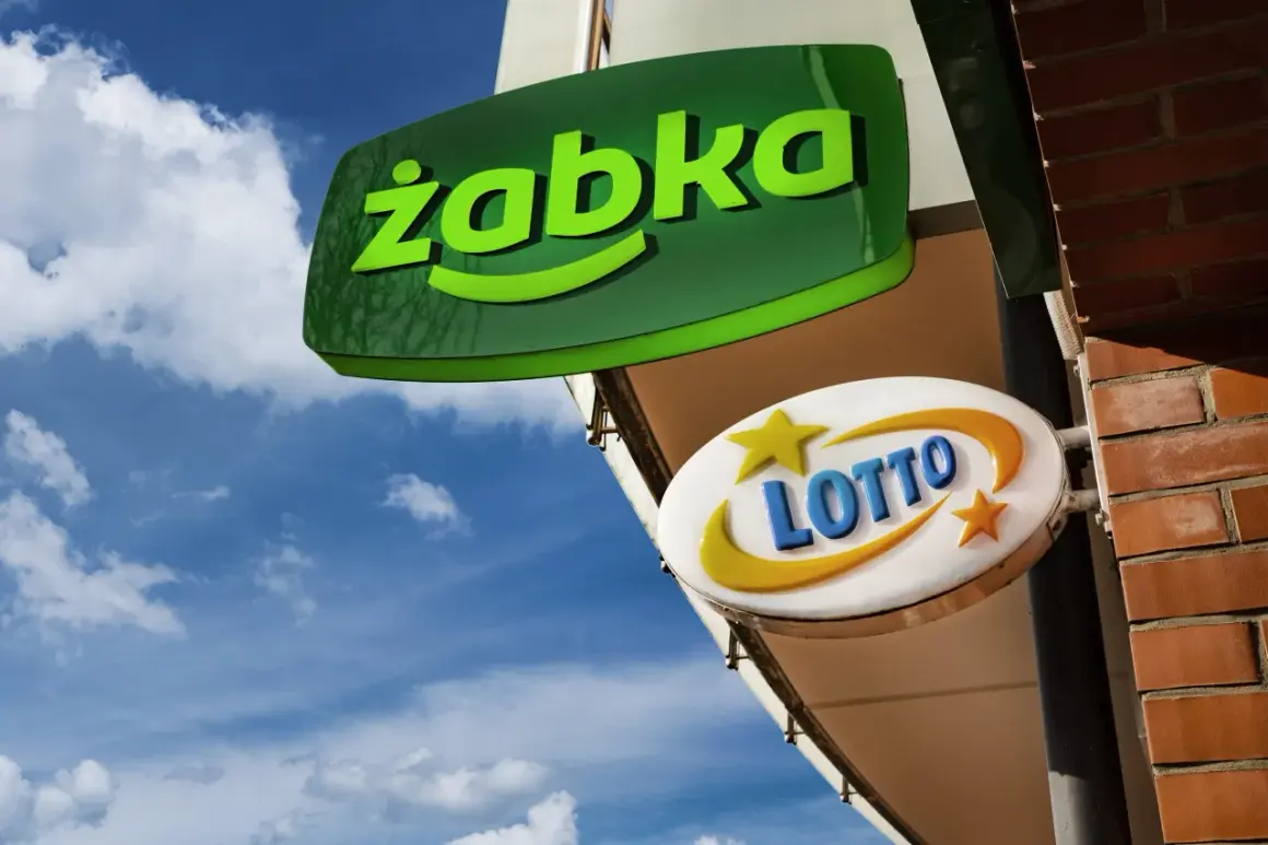 Zielona tablica "Żabka" i biała z napisem "LOTTO" wiszą na tle błękitnego nieba z chmurami.