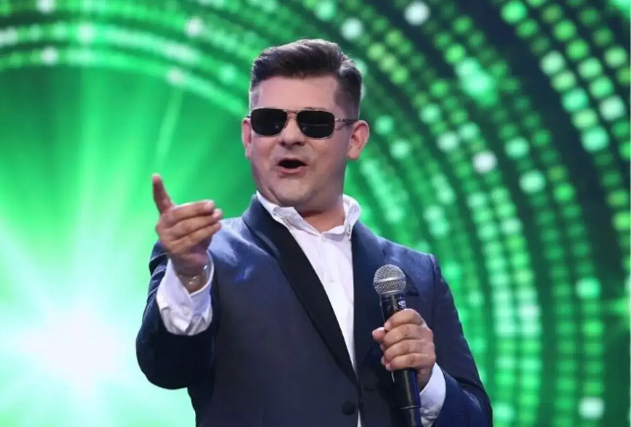 Gwiazdor disco polo w okularach i garniturze śpiewa do mikrofonu. Może to wyjaśnia, dlaczego polskie gwiazdy disco polo chwalą się wygranymi w zdrapkach na IG.