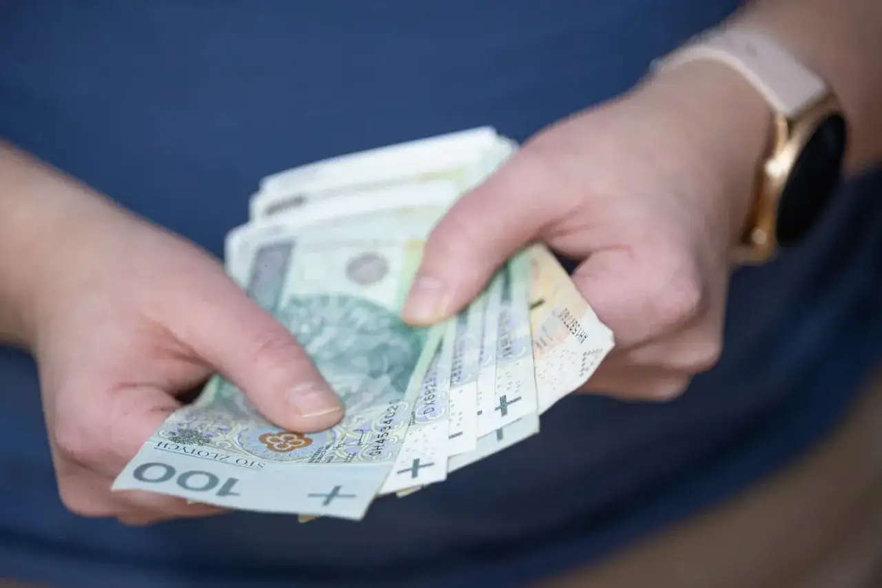 Dłonie trzymające polskie banknoty. Czy można wymienić nagrodę rzeczową z loterii kredytowej na gotówkę?
