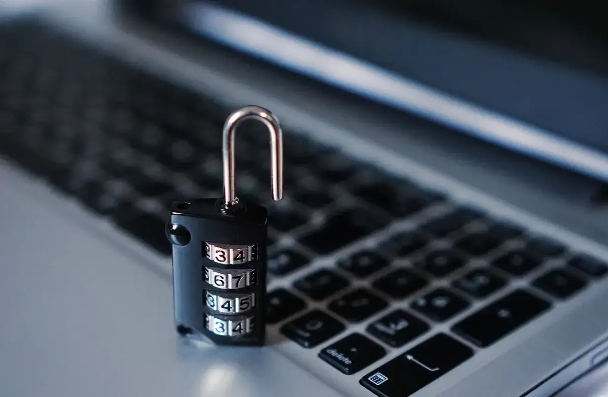 Kłódka szyfrowa na klawiaturze laptopa. Prawda o rzekomych darmowych pożyczkach dla stałych klientów biorących udział w grach - bezpieczeństwo danych jest kluczowe.