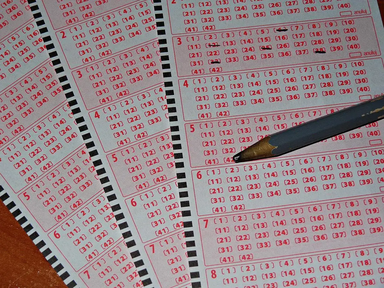 Kaskada wyników sprawdzana ołówkiem na kuponach lotto. Liczby czekają na swoje szczęśliwe kombinacje.