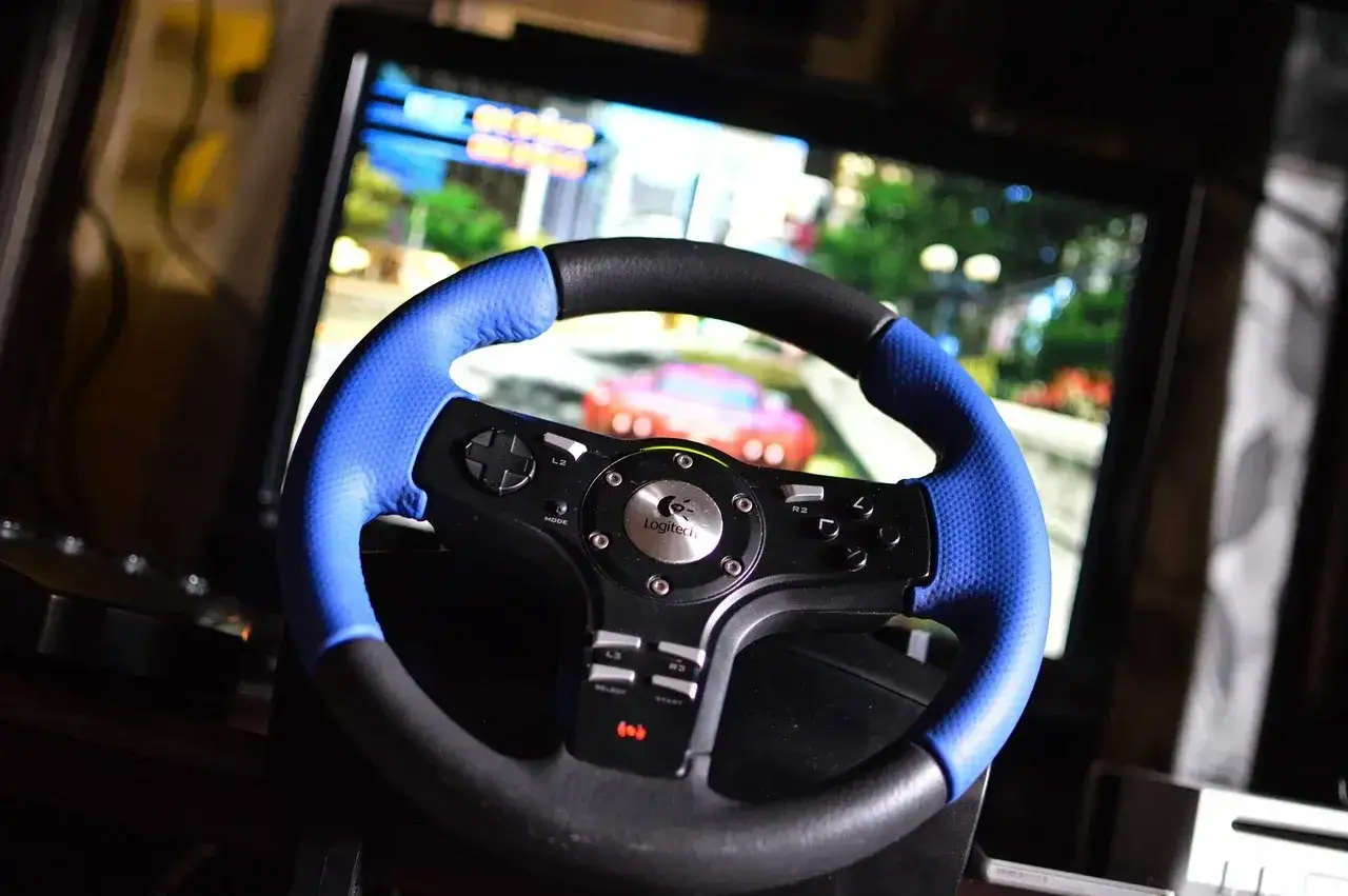 Kierownica Logitech z niebieskimi akcentami i ekranem gry w tle. Uczestnicy eliminacji muszą spełnić określone wymagania techniczne, by móc wystartować.