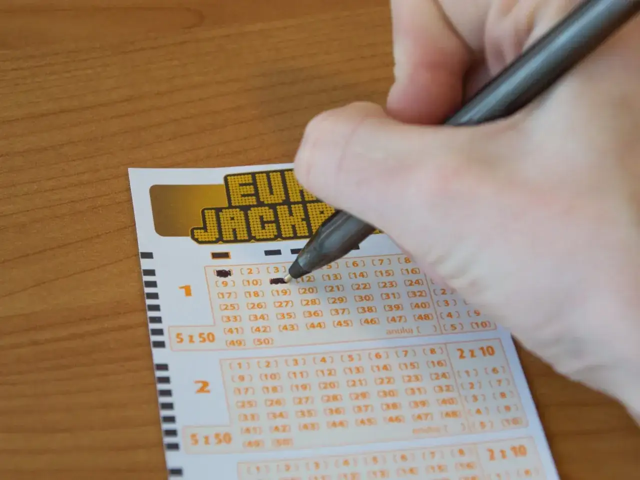 Ręka zaznacza liczby na kuponie Eurojackpot. Czy Totalizator Sportowy blokuje wypłaty wygranych z Eurojackpot w Polsce?