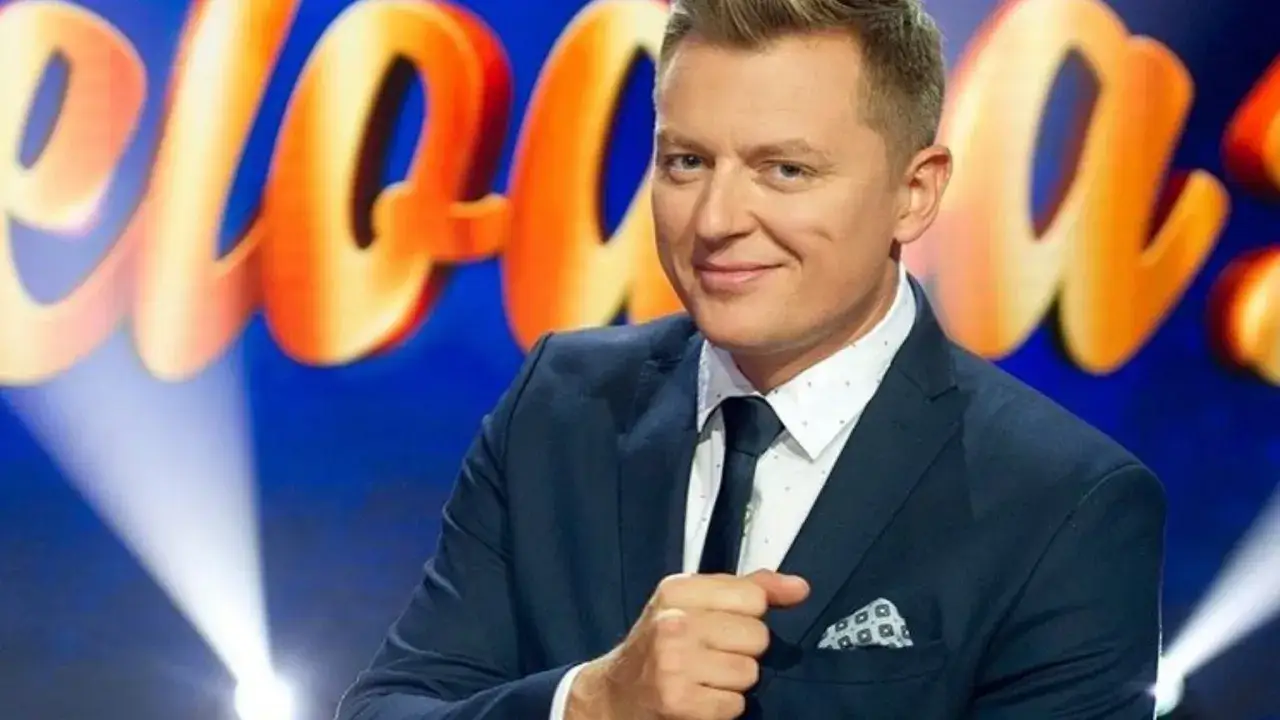 Uśmiechnięty prowadzący w garniturze na tle logo
