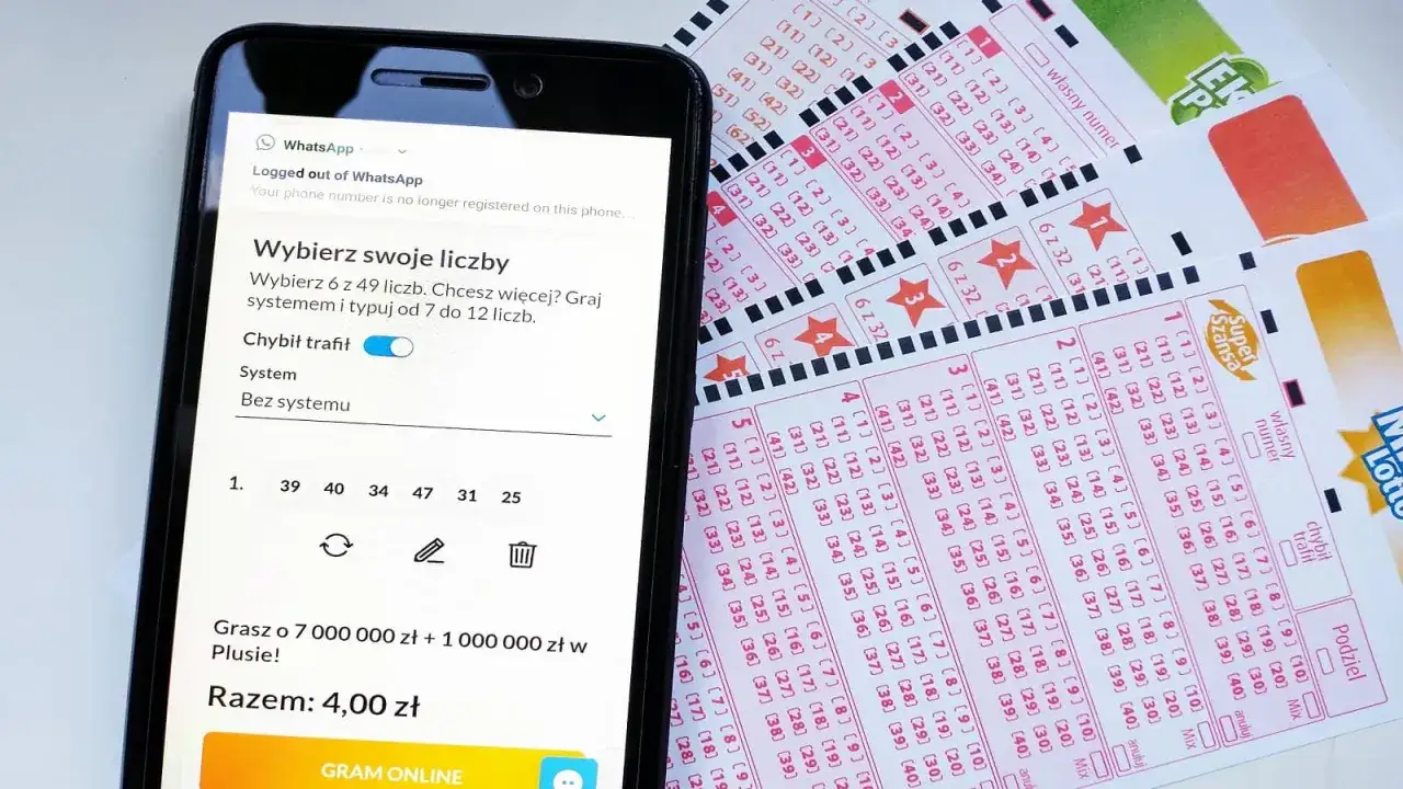 Telefon z aplikacją do gry w lotto obok papierowych kuponów. Marzenia o lotto wysokie wygrane stają się bliższe dzięki nowoczesnej technologii.