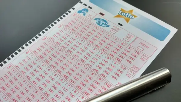 Kupon Lotto z zaznaczonymi polami do wyboru liczb i długopisem.