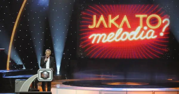Prowadzący w studiu "Jaka to melodia?" z mikrofonem. Zastanawiasz się, ile kosztuje minuta reklamy w trakcie trwania tego programu?