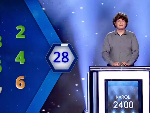 Karol Fedoruk w studiu telewizyjnym, obok planszy z liczbami i wynikiem 2400.