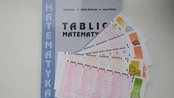 Książka "Tablice Matematyki" obok kuponów lotto. Czy matematyka pomoże wybrać gorące liczby lotto?
