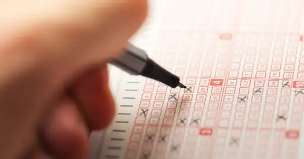 Ręka zaznacza liczby na kuponie lotto. Odkryj sekrety produkcji losowań lotto na żywo, czego nie widzą widzowie.