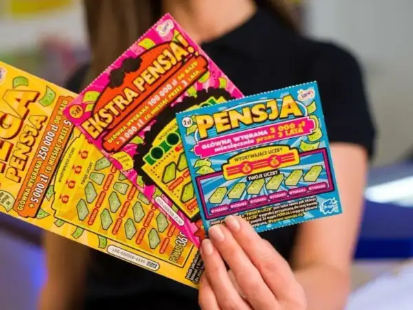 Kobieta trzyma zdrapki lotto z hasłem "Ekstra Pensja". Tabela wygranych pokazuje szansę na dużą wygraną.