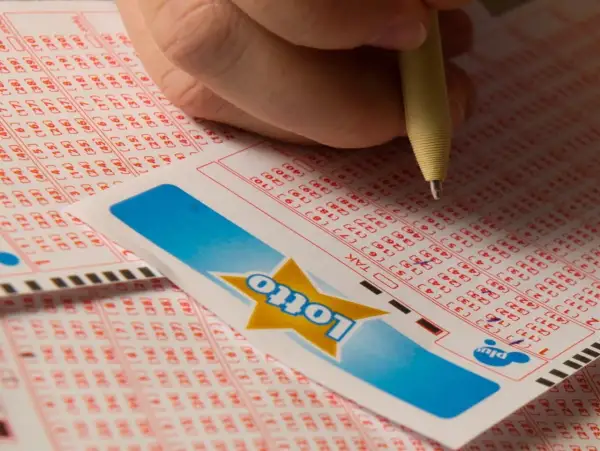 Dłoń zaznacza liczby na kuponie Lotto. Czy to będą zwycięskie lotto kaskada wyniki?